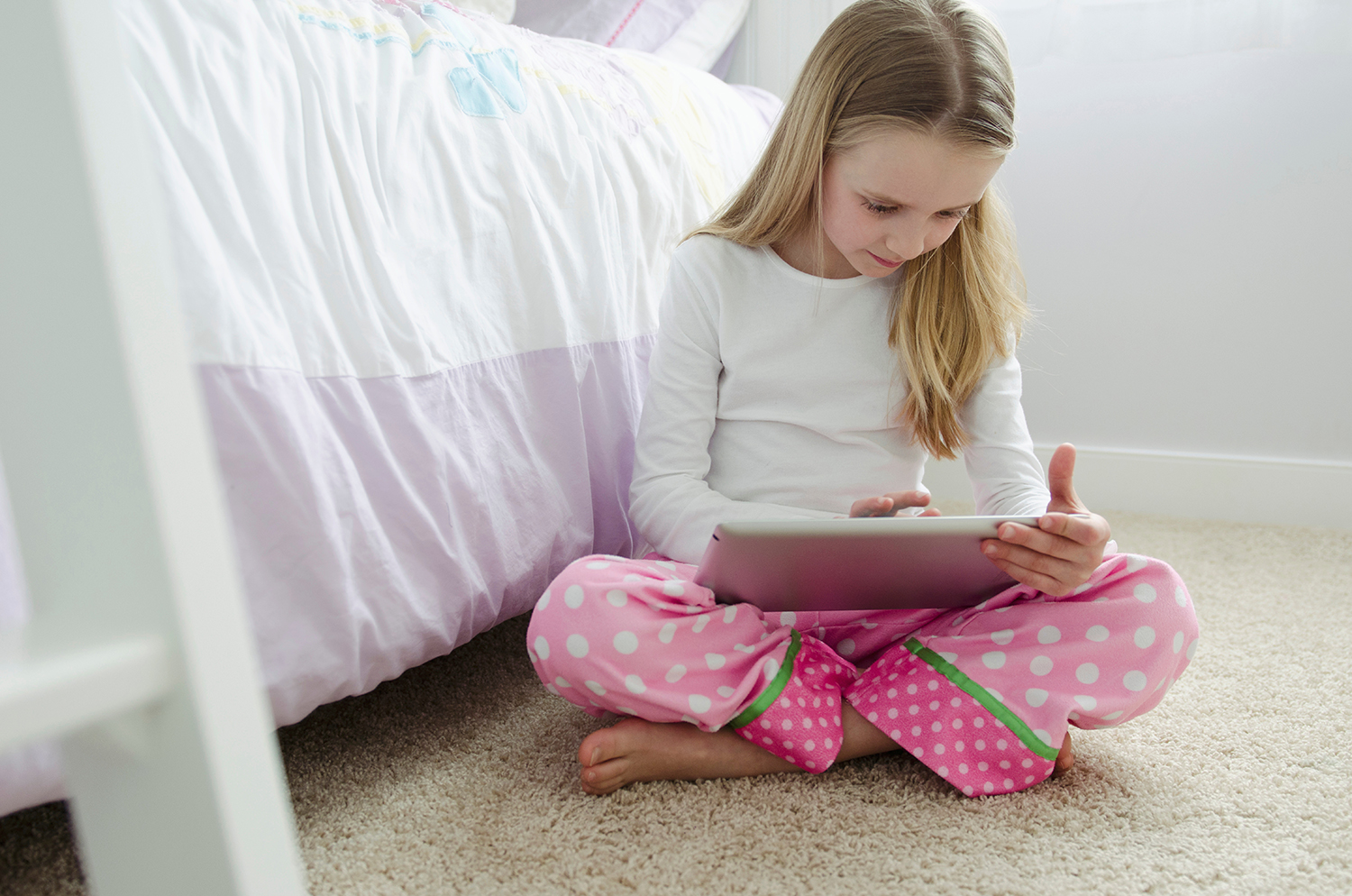 young girl playing on ipad in bedroom